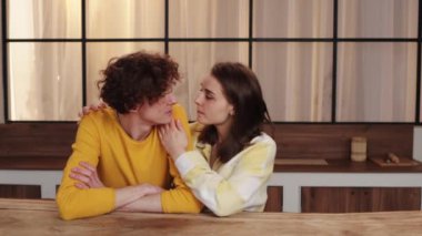 Samimi giyimli bir çift sıcak ve huzurlu bir ortamda ahşap bir masada samimi bir anı paylaşıyor.