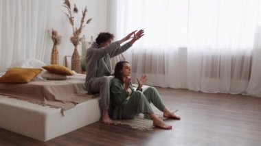 Bir çift, büyük pencereli, aydınlık, rahat bir oturma odasında birlikte rahat bir anın tadını çıkarıyor..