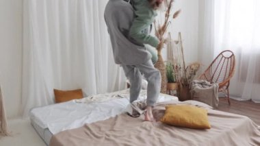 Çift, parlak, rahat ve minimalist yatak odası ortamında bir yatakta eğleniyor ve eğleniyor..