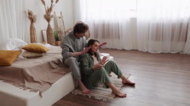 Pijamalı bir çift, doğal dekorlu ve yumuşak ışıklandırmalı, rahat, modern bir yatak odasında ateşli bir şekilde tartışıyor..