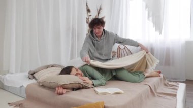 Bir insanın kitap okuduğu samimi bir yatak odası diğerini nazikçe uyandırırken sıcaklık, huzur ve beraberlik saçıyor. Ağır çekim, 4k