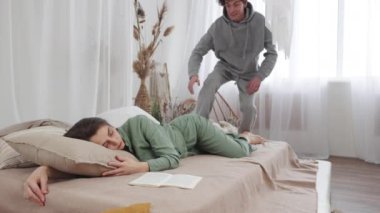 Rahat bir yatak odasında rahatlatıcı bir sabah geçiren genç bir çift rahatlık, sevgi ve rahatlama sergiliyor..