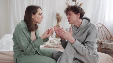Evdeki bir çift hararetli bir şekilde tartışıyor, duygularını ifade ediyor ve el hareketleriyle birbirleriyle iletişim kuruyor.