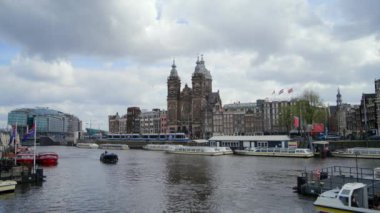 AMSTERDAM, NETHERLANDS - 11 NİSAN 2023 Şok edici manzara tarihi binalar, büyüleyici tekneler ve büyüleyici bir gökyüzü içeriyor, şehirlerin eşsiz mimarisini ve canlı atmosferini vurguluyor