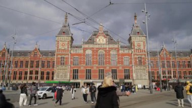 AMSTERDAM, NETHERLANDS - 11 Nisan 2023. Nefes kesici ikonik merkez tren istasyonu eşsiz mimari tasarımını ve insanlarla dolu hareketli atmosferini gözler önüne seriyor.