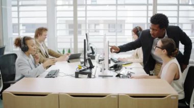 Modern bir ofis ortamında çalışan çeşitli profesyonellerden oluşan bir ekip, verimli bir şekilde birlikte çalışıyor, takım çalışması, teknoloji ve üretkenliği vurguluyor.