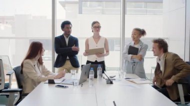 Modern bir ofiste gerçekleştirilen başarılı bir iş toplantısında çeşitli genç profesyoneller, dinamik ve yenilikçi bir ortamda projeleri tartışmak ve kurumsal hedeflere ulaşmak için işbirliği yaparlar.