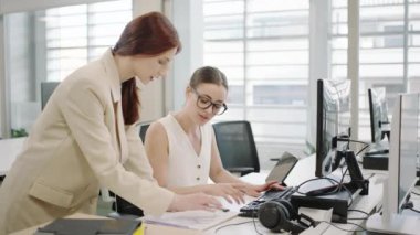 İki genç profesyonel modern bir ofiste işbirliği yapıyor, iletişim kuruyor ve bilgisayar ve evrak işleriyle çevrili proje görevlerine yoğunlaşıyor. Takım çalışmasını ve üretkenliği somutlaştırırlar.