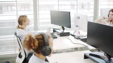 Video, üretkenlik ve işbirliğini artırmak için teknoloji ve takım çalışmalarından yararlanan, modern ofis ortamında birlikte çalışan çeşitli genç çalışanlardan oluşan bir grubu gösteriyor.