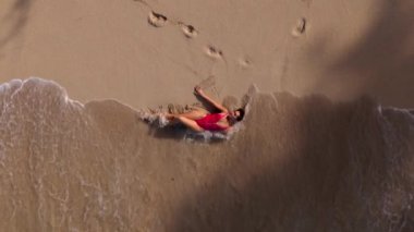 Büyüleyici bir hava manzarası, Oahu, Hawaii 'nin altın kumlarında huzur içinde dinlenen bir insanı yakalar. Yumuşak dalgalar, büyüleyici bir günbatımında yavaşça kıyıya vurur ve güzel bir manzara yaratır.