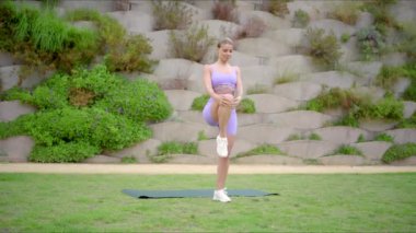 Spor meraklısı bir sporcu, açık havada renkli bir yoga minderi üzerinde atletik egzersizler yaparak gücünü, dengesini ve esnekliğini gösterir.