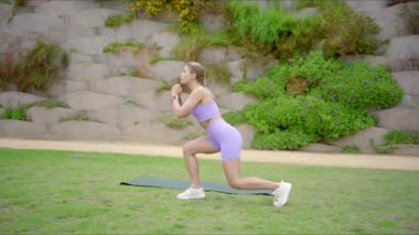 Formda, enerjik genç bir kadın, olağanüstü gücünü ve canlılığını, sakin bir açık hava ortamında yoga minderinde çeşitli egzersizler yaparak sergiliyor.