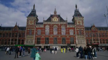 AMSTERDAM, NETHERLANDS - 11 Nisan 2024. Amsterdam Merkez İstasyonu 'nun nefes kesici zaman çizelgesi, hareketli ve enerjik kalabalıkla birlikte onun karmaşık ve etkileyici mimarisini yakalıyor.