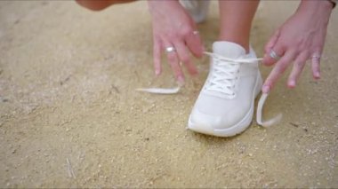 Kararlı bir kadın sıcak kumda oturur, en sevdiği spor ayakkabılarını bağlar, gücünü, bağlılığını, sağlık ve refahını gösteren enerji verici bir egzersize hazırdır.