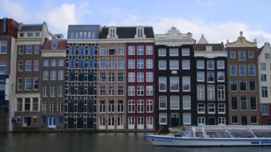 AMSTERDAM, NETHERLANDS - 11 Nisan 2024. Amsterdam 'daki geleneksel kanal evleri, turist şehri manzarası, dingin rıhtım boyunca canlı renkler, güzel bir manzara.