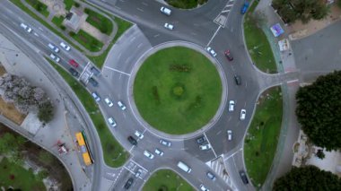 Bu hava görüntüsü, hareketli bir Sevilla kavşağının hareketli aktivitesini yakalar, dinamik trafik akışı ve yemyeşil alanlar şehrin kentsel manzarasını ve atmosferini güçlendirir.