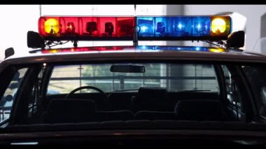 Görüntü, polis aracının parlak kırmızı ve mavi yanıp sönen ışıkları, kolluk kuvvetlerini, kamu güvenliğini, toplum korumasını ve polisin yardım etmeye hazır olduğunu simgeleyen yakın çekimini gösteriyor.