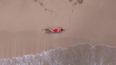 Oahu, Hawaii 'de sakin bir plajda uzanan bir kadının nefes kesici bir görüntüsü, güneşin doğuşunun resimli anında, yumuşak okyanus dalgalarını ve yumuşak, sıcak kumları vurguluyor.