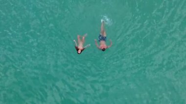 Bu çarpıcı hava aracı, Oahu, Hawaii 'nin canlı, kristal berrak sularına dalmış iki neşeli yüzücüyü güzel bir şekilde yakalar.