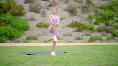 Sağlıklı bir kadın açık havada renkli bir yoga minderi üzerinde egzersiz yapıyor, zindeliğin ve sağlığın yaşam ve refahımızı arttırmadaki önemini vurguluyor, gelişmemize ve enerji kazanmamıza yardım ediyor.