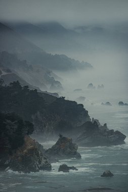 Kaliforniya, Big Sur 'un sisli kıyı şeridinin nefes kesici, sakin manzarası. Derin mavi sularda yükselen dramatik uçurumlar ve dalgalar büyüleyici ve büyüleyici bir atmosfer yaratır.