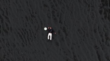 Yukarıdan çekilen bu resim, İzlanda 'nın izolasyon ve saf güzelliğini somutlaştıran, katıksız siyah volkanik kumun üzerinde uzanan, dokulu yüzeyle çarpıcı bir tezat oluşturan yalnız bir insanı gösteriyor. 