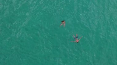 Bir hava aracı Oahu 'nun dingin ve berrak turkuaz sularının tadını çıkaran yüzücüleri güzel bir şekilde yakalar. Nefes kesici bir güneşin doğuşu veya batışının çarpıcı ve canlı renkleriyle zarifçe aydınlatılır.