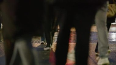 Canlı ve dinamik bir şehir sahnesinde kalabalık ve hareketli bir cadde sergileniyor. Birçok insan gecenin büyüleyici saatlerinde birlikte yürüyor ve hareketli bir atmosfer yaratıyor.