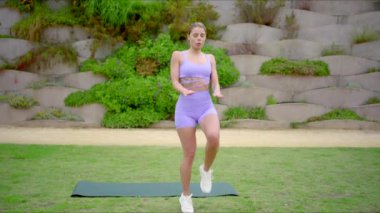 Manzaralı bir açık hava ortamında, sağlıklı bir kadın yoga pratiği yapar, atletizmini ve çevresine ilham veren enerjik bir yaşam tarzına bağlılığını gösterir.