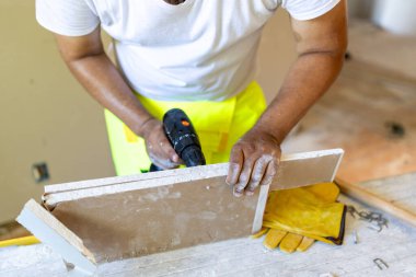 Becerikli bir inşaat işçisi yenileme, güvenlik teçhizatı altını çizmek, olağanüstü işçilik ve yenileme projesi sırasında detaylara özen göstermek için güçlü bir matkap kullanır.