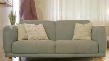 Genç Afro-Amerikan erkeği, rahat ve rahat bir koltukta otururken mutlu ve keyifli bir şekilde cep telefonunu karıştırıyor. Keyif almanın mükemmel bir örneğini sunuyor.