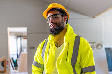 Güvenlik yeleği ve miğfer takan çalışkan bir inşaat işçisinin eşlik ettiği neşeli bir mimar, büyük bir coşku ve odaklanma ile karmaşık ev yenileme projesini aktif olarak denetliyor.