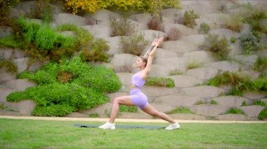 İnanılmaz güçlü ve atletik bir kadın, sakin ve sakin bir açık hava ortamında etkileyici bir yoga pozu veriyor. Hem zindeliğini hem de zarifliğini güzelce sergiliyor.