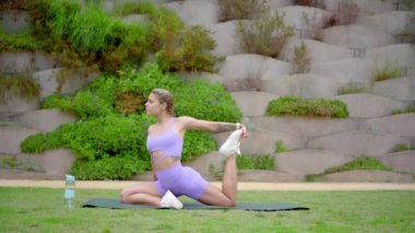 Güçlü ve güzel bir kadın, verimli bir açık hava ortamının ortasında etkileyici bir yoga pozu sergiliyor. Spor meraklıları ve yoga aşıkları için mükemmel bir atmosfer yaratıyor.
