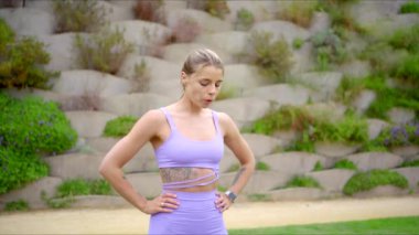 Güzel bir fitness kadını dışarıda egzersiz yaparken atletizmini sergiliyor, doğal güzellik ve enerjiyle dolu canlı bir ortamda sağlığına ve sağlığına olan bağlılığını vurguluyor.