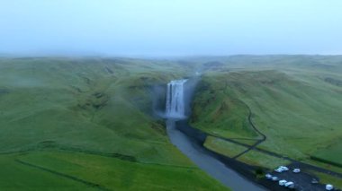 İzlanda 'nın nefes kesici güzelliğine dalın, İzlanda şelalesi Skogafoss dingin yeşil manzaraların ortasındaki görkemli şelalenin büyüleyici hava görüntülerine, sükunet ve doğal cazibeyi gösterin.