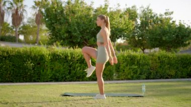 Kendini adamış genç bir fitness meraklısı, düzenli güç ve esneklik egzersizleriyle sağlıklı ve aktif bir yaşam tarzına olan bağlılığını gösteren renkli bir yoga minderi üzerinde hamlesini yapıyor.