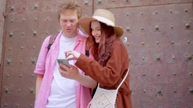 Akıllı telefonlarına dalmış neşeli bir çift, açık havada oturur, gülümser ve canlı atmosferi kucaklarlar, modern bağlantıyı ve gerçek mutluluğu birlikte hoş bir anda sergilerler.