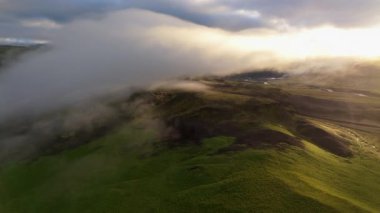 Dramatik hava görüntüleri, güneşin doğuşu sırasında yoğun sisle kaplanmış verimli İzlanda arazisini yakalar ve manzaranın zıt renklerini ve dokularını vurgular. İzlanda. 