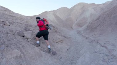 Tutkulu ve adanmış turistler, Ölüm Vadisi Ulusal Parkı 'ndaki engebeli kayalık arazide dikkatli bir şekilde yürürler. Sıcak güneşin altında ağır bir sırt çantasıyla, ustalıkla araziyi dolaşırlar.