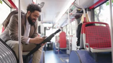 Afrika kökenli Amerikalı bir işadamı, neredeyse boş bir halk otobüsünde rahat bir şekilde otururken akıllı telefonunu kontrol ediyor ve bugün modern bir şehir ortamında kentsel dönüşüm deneyimini sergiliyor.