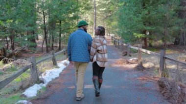 Yosemite Ulusal Parkı 'nda, nefes kesici kış güzellikleri, görkemli yüksek ağaçlar ve doğanın sakin atmosferiyle çevrili, el ele gezen neşeli bir çift el ele yürüyor.