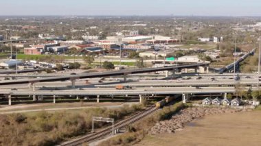 Sinematik hava görüntüsü, Houston 'da hareketli ve hareketli bir şehir manzarası içinde etkin demiryolları ile karmaşık bir şekilde birbirine karışan otoyol değişimine dikkat çekici bir perspektif sunuyor.