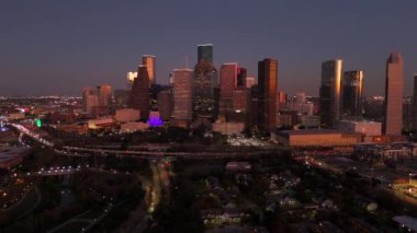 Houston, Teksas 'ın nefes kesen hava manzarası alacakaranlıkta aydınlatılan göz kamaştırıcı gökyüzünü aydınlatıyor. Canlı, renkli ışıklar ve çarpıcı mor gökyüzü ile büyüleyici bir atmosfer yaratıyor.