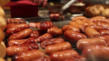 Canlı ve hareketli bir gıda pazarında, çeşitli ızgara sosisler sergilenen baştan çıkarıcı bir gösteri var, hepsi canlı renkler, baştan çıkarıcı dokular ve ağız sulandıran aromalar.