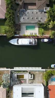 Sinema sahnesi, Miami Beach, Florida 'nın güneyindeki güzel evleri, parlak havuzları ve kanalizasyon adalarının etrafındaki su yollarına kenetlenmiş çeşitli tekneleri gösteriyor.