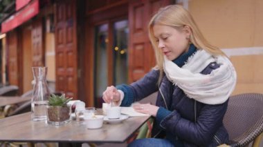 Kırsal cazibe ve sükunetle çevrili açık bir kafede kahvesini yudumlayan genç bir kadının huzurlu bir anı.