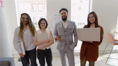 Başarılı iş kadınlarından oluşan canlı bir çok kültürlü grup ve seçkin bir işadamı modern bir ofiste dizüstü bilgisayarlarla poziyonlarını vererek pozitiflik ve takım çalışması için gerekli işbirliği sağlıyorlar.