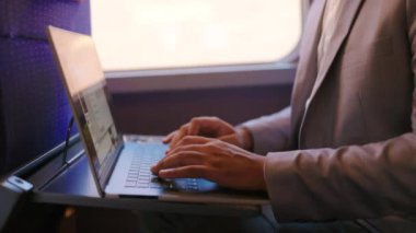 Bir trende rahat bir şekilde otururken dizüstü bilgisayarına derinden konsantre olan Afrikalı bir iş adamı, geçiş yolculuğu sırasında üretkenlik ve verimliliğin büyüleyici bir karışımını sergiliyor.