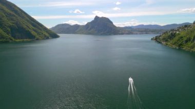 Como Gölü 'nün havadan görünüşü, berrak sularını görkemli dağları yansıtırken, sakin yüzey boyunca süzülen küçük bir tekne, dinlenmek için huzurlu bir atmosfer yaratıyor.